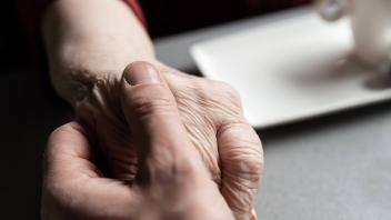 Close up of the hands of a 43 year old white man holding the hands of his 83 year old mother, Tienen
