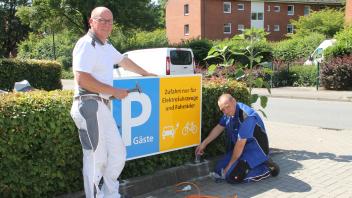 Verbrenner müssen draußen bleiben: Die bgm-Handwerker Thomas Haß (links) und Kurt Suhr beim Einbau des neuen Parkplatzschildes.