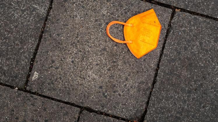 ARCHIV - Ein gebrauchter orangefarbener Mund-Nasen-Schutz liegt auf dem Gehweg. Foto: Peter Kneffel/dpa/Symbolbild