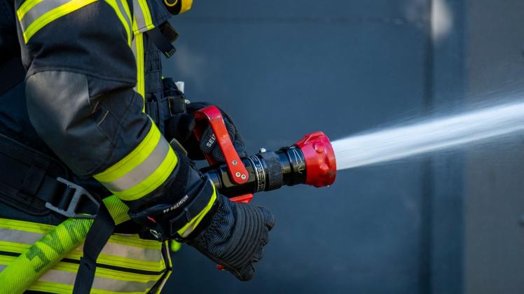 PRODUKTION - Ein Mitglied der Feuerwehr spritzt aus einem Schlauch mit Wasser. Foto: David Inderlied/dpa/Symbolbild
