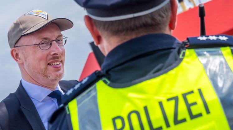 ARCHIV - Mecklenburg-Vorpommerns Innenminister Christian Pegel (SPD, l) spricht mit einem Polizisten. Foto: Jens Büttner/dpa/Archivbild