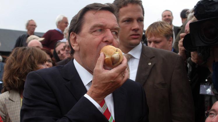 Viele deutsche Klischees in einem Bild: Der damalige Bundeskanzler Gerhard Schröder lässt sich2005 bei einer Wahlkampfveranstaltung in einem Kleingartenverein eine Wurstsemmel schmecken.