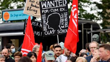 Ein Demonstrant gegen Kanzler Olaf Scholz hält ein Plakat mit den Worten Wanted for: Cum Ex in die Höhe auf der DGB-Vera