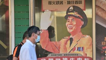 This picture taken on August 10, 2022 shows people walking past an advertisement portrait of the late president Chiang Kai-shek at Kinmen islands. (Photo by Sam Yeh / AFP)