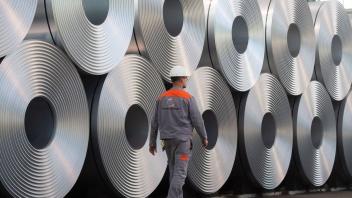 ARCHIV - Eine Mitarbeiter geht bei der Salzgitter AG an aufgewickeltem Stahl vorbei. Foto: Julian Stratenschulte/dpa/Symbolbild