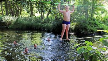 Max (10) aus Rendsburg balanciert die „Schleckerleine“, wie die Kinder die Slackline über der Warnow nennen, entlang, um dann, wie schon die im Wasser schwimmenden Kinder vor ihm, in den Fluss zu springen