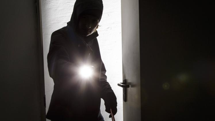 Symbolbild zum Thema Einbruch Gestellte Aufnahme Ein Mann steht mit einer Taschenlampe in einer ge