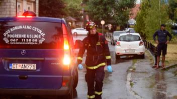 Ein Feuerwehrmann geht an einem Leichenwagen am Ort des Amoklaufs vorbei. Foto: Risto Bozovic/AP/dpa