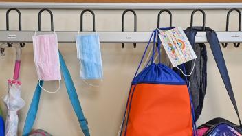 ARCHIV - Masken hängen zusammen mit Taschen und Rucksäcken an Kleiderhaken in einem Klassenraum einer Grundschule. Foto: Patrick Pleul/dpa-Zentralbild/ZB