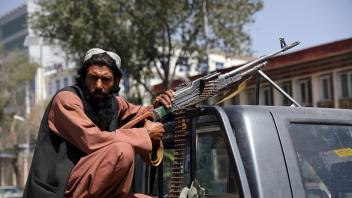 ARCHIV - Ein Taliban-Kämpfer sitzt in Kabul mit einem Maschinengewehr auf der Ladefläche eines Fahrzeugs. Foto: -/AP/dpa