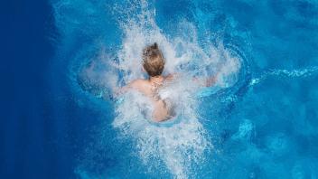 Ein Junge springt in einem Freibad ins Wasser. Foto: Joerg Carstensen/dpa/Symbolbild
