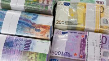 ARCHIV - Bündel von Banknoten in Franken und Euro liegen auf einem Tisch. Foto: Martin Ruetschi/KEYSTONE/dpa/Symbolbild