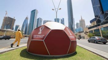 ARCHIV - Ein Werbedisplay für den «FIFA World Cup Qatar 2022» steht auf einem Grünstreifen vor dem Doha Exhibition & Convention Center (DECC). Foto: Christian Charisius/dpa