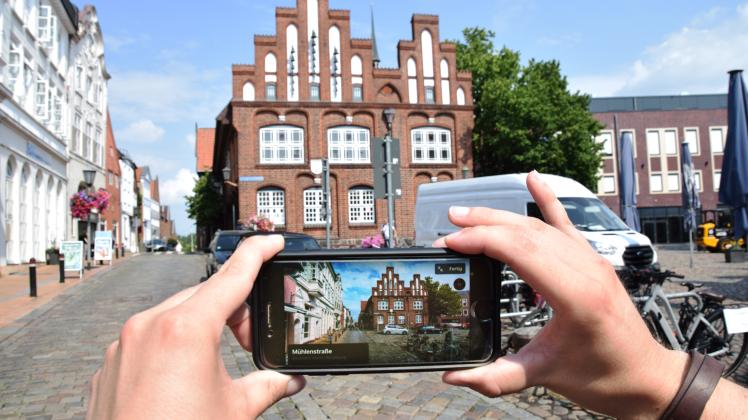 Das Alte Rathaus der Stadt Rendsburg in der „Look Around“-Ansicht auf dem Handy und dahinter im Original. 