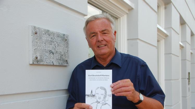 Bernd Nissen mit seinem Buch über den Grafen Brockdorff-Rantzau vor dessen Geburtshaus im Schleswiger Stadtweg 59.