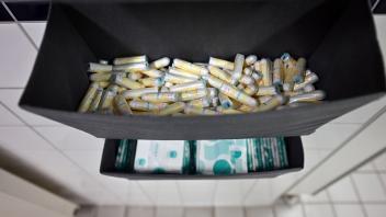 ARCHIV - Damenbinden und Tampons liegen in einem Behälter auf einer Toilette. Foto: Martin Schutt/dpa/Symbolbild