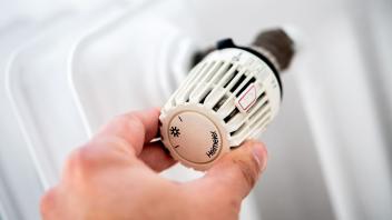 ILLUSTRATION - Ein Mann dreht am Thermostat einer Heizung. Foto: Hauke-Christian Dittrich/dpa/Symbolbild