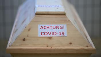 ARCHIV - Ein Sarg mit der Aufschrift «Achtung! Covid-19». Foto: Felix Kästle/dpa/Archivbild