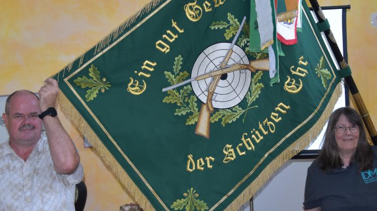 Schützenheim Quickborn: Vorsitzender Ralph Nolde und Schützenmeisterin Birgit Bruhn zeigen die Vereinsflagge