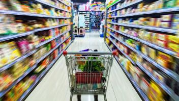 Supermarket shopping cart in the middle of a shelf filled with dynamic blur effect of goods PUBLICATIONxNOTxINxCHN 75802