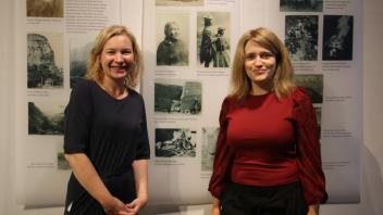 Museumsleiterin Katharina Gräber (l.) und Ausstellungskuratorin Janina Willems stehen vor der Fotowand mit Habliks Reiseeindrücken.