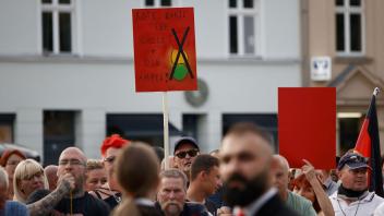 Zuschauer protestieren während der Rede von Bundeskanzler Olaf Scholz bei einer Dialogveranstaltung Bürgern in Neuruppin. Foto: Carsten Koall/dpa