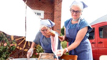 Heike Glug und Maria Hollensen demonstrieren „Weißwäsche“, wie sie traditionell bearbeitet wurde.