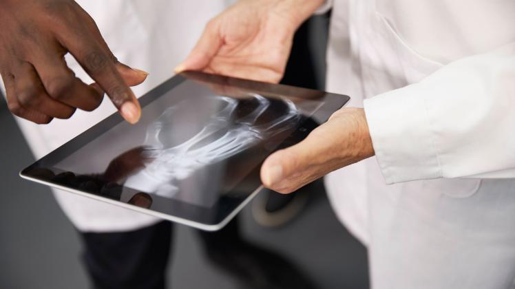 Doctor with colleague holding tablet PC with X-ray image at hospital model released property released, PMF02145