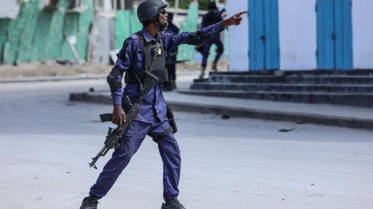 A security officer gestures as he and colleagues patrol at the the site of explosions in Mogadishu on August 20, 2022. - At least eight civilians have been killed in an Islamist militant attack on a popular hotel in the Somali capital, an official said, as security forces continued to battle gunmen barricaded inside. (Photo by Hassan Ali ELMI / AFP)