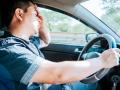 Übermüdeter Fahrer im Stau, Konzept eines übermüdeten Mannes in seinem Auto, gestresst. Ein Fahrer mit Kopfschmerzen im