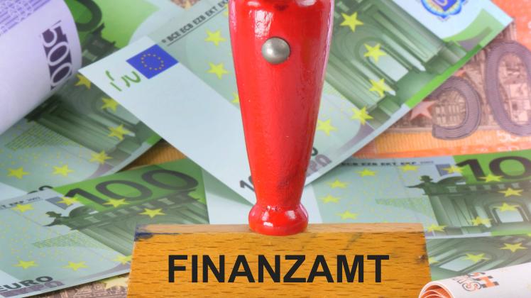 Stempel mit Aufdruck Finanzamt mit Geldscheinen und Euromuenzen zum Thema Steuern. Symbolbild zum Thema Steuern und Fina