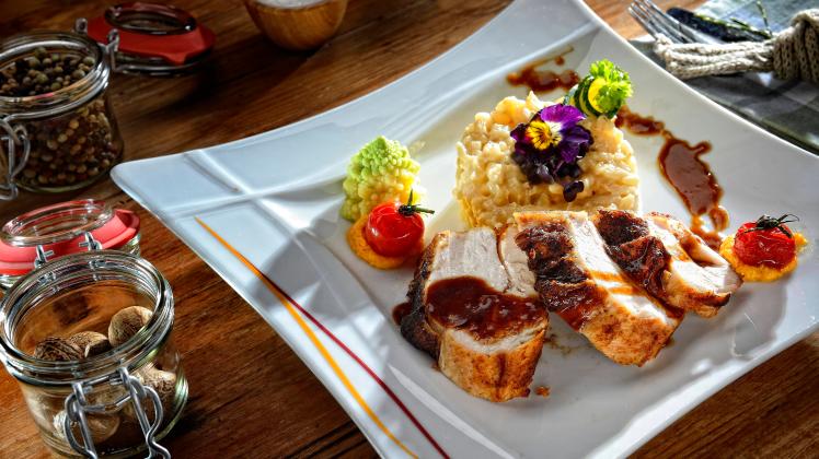 Putenbrust mit Soße und Risotto, angerichtet auf Teller *** Turkey breast with sauce and risotto, served on a plate Copy