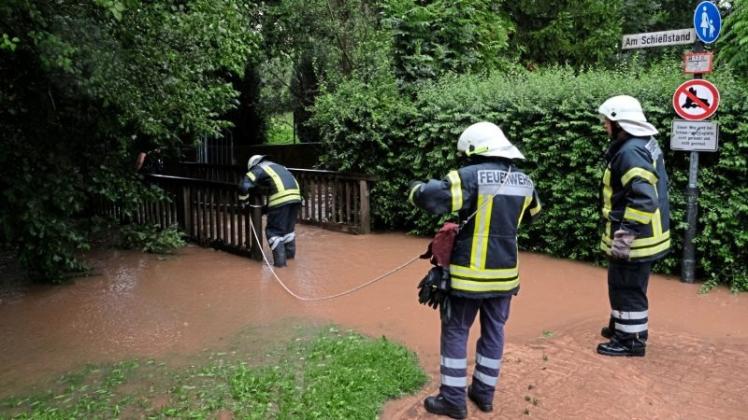 Feuerwehrmänner sichern am 25.07.2017 eine Brücke, die vom Wasser eines einem übergelaufenen Bachs in Springe (Niedersachsen) überschwemmt wird. Dauerregen hat im südlichen Niedersachsen in einigen Orten zu Überschwemmungen geführt. 