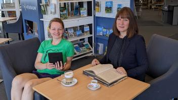 Die Bibliotheksmitarbeiterinnen Jennifer Lübker (li.) mit einem E-Reader und Bianca Engel mit einem der wenigen erhalten gebliebenen historischen Bücher aus den Anfängen der Stadtbücherei Ahrensburg.