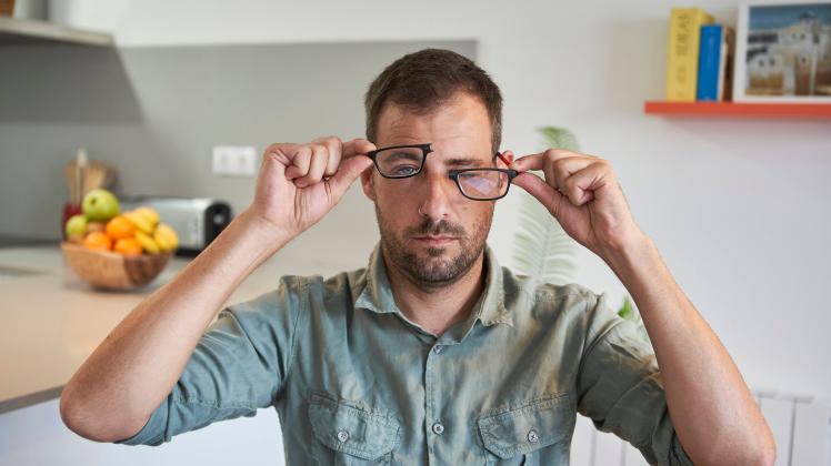 Mid adult man holding broken eyeglasses while sitting at home model released Symbolfoto property released VEGF02983