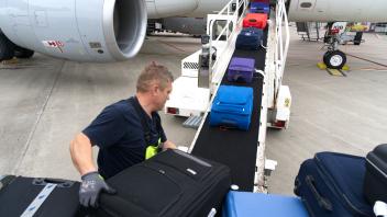 Ein Mitarbeiter belädt am FMO ein Flugzeug mit Koffern.