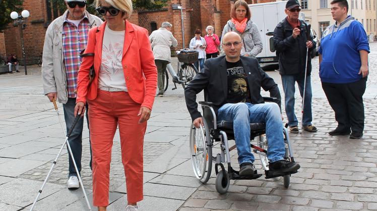 Frau mit Blindenstock und Mann im Rollstuhl