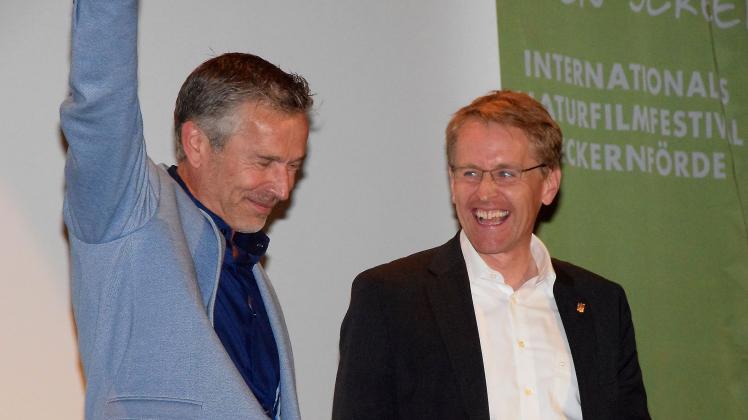 Geschafft! Das 16. Internationale Naturfilmfestival Green Screen ist eröffnet - Festivalleiter Dirk Steffens reckt den Arm, Ministerpräsident Daniel Günther ist die große Freude anzumerken.