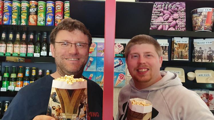 Nach dem Probelauf der Popcorn-Maschine prÃ¤sentieren Kai Bartels (links) und Onno Dreibholz, getrennt durch eine Scheibe, das Ergebnis ihrer Arbeit. Ab heute Nachmittag wird die Leckerei zum Mitnehmen verkauft.