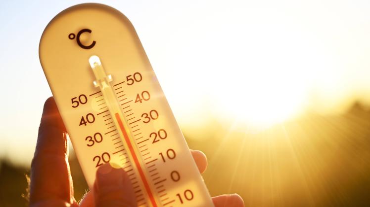 FOTOMONTAGE, Hand hält Thermometer bei über 30 Grad Celsius, Symbolfoto Hitzewelle *** PHOTOMONTAGE, hand holding thermo