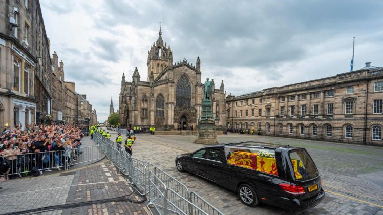 The hearse carrying the coffin of Queen Elizabeth II, draped in the Royal Standard of Scotland, is driven past St Giles&apos; Cathedral in Edinburgh, en-route towards the Palace of Holyroodhouse, on September 11, 2022. - The coffin carrying the body of Queen Elizabeth II left her beloved Balmoral Castle on Sunday, beginning a six-hour journey to the Scottish capital of Edinburgh. (Photo by Andrew O&apos;Brien / AFP)