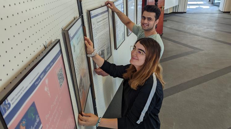 Die Schüler Dilan Köygülü (vorne) und Firaas Sheikh hängen die Plakate der Ausstellung im Rathaus auf.