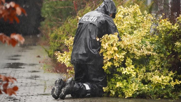 Nach dem tödlichen Schuss am Silvestermorgen 2022 sucht ein Polizist auf dem Gelände der Lagerhalle in Neumünster im Regen nach Spuren.                              