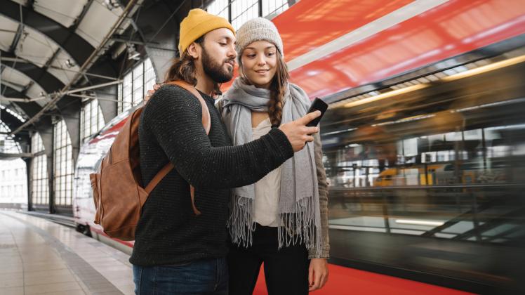 Young couple using smartphone at the station platform as the train comes in, Berlin, Germany model released Symbolfoto P