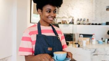 Smiling woman with Afro hairstyle holding coffee cup model released, Symbolfoto property released, JCCMF06706