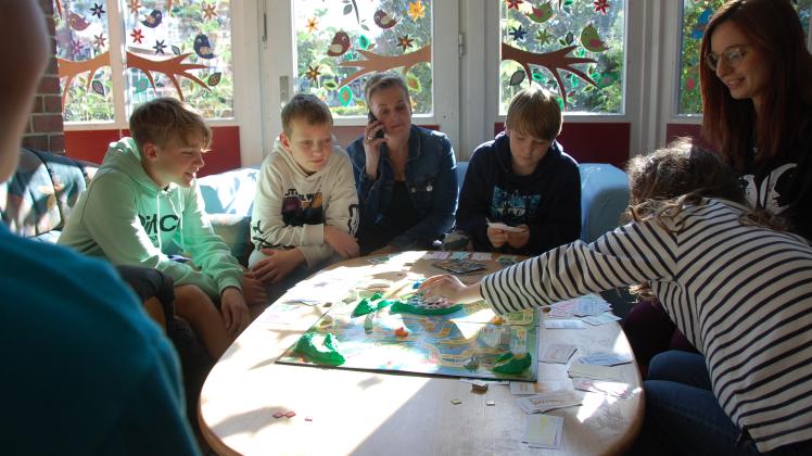 Spielen zusammen das Brettspiel „Spiel des Lebens“ (von links), Tamino (türkisfarbener Pullover), Lucca, Petra Christiansen, Finn, Daniela Nebel und Lara.