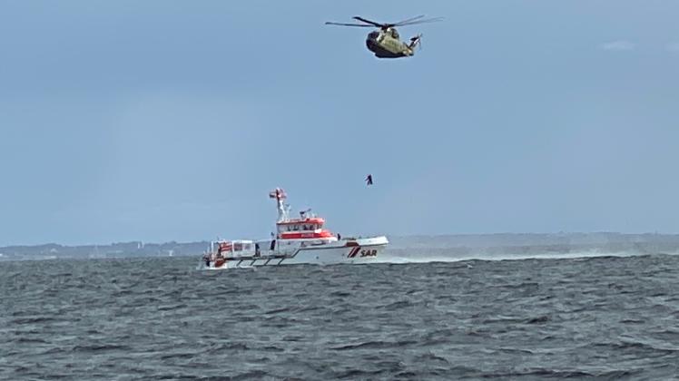 Ein geretteter Schiffbrüchige wird vom Hubschrauber per Winde auf den Seenotrettungskreuzer BERLIN der Deutschen Gesellschaft zur Rettung Schiffbruechiger (DGzRS) abgeseilt (Einsatz am 17.9.22)