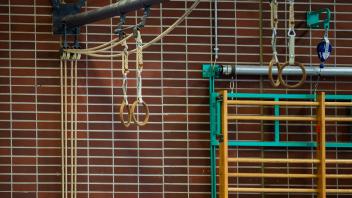 Turnringe hängen an der Decke in einer Sporthalle. Foto: Kirchner-Media/Wedel *** Gymnastic rings hanging from the ceili