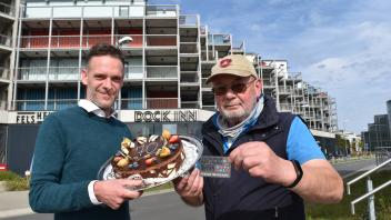 Dock-Inn-Chef Christoph Krause gratuliert Stammgast Axel Neumann zum 70. Geburtstag mit einer Torte. Axel war der erste Gast und genießt seit dem bei jeder Buchung einen Rabatt von 50 Prozent. 
