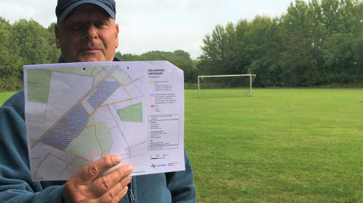 Bürgermeister Jens Krügel präsentiert den Plan, der zeigt, auf welchen drei Flurstücken der Solarpark Arpsdorf entstehen soll. Die Flächen sind blau schraffiert.